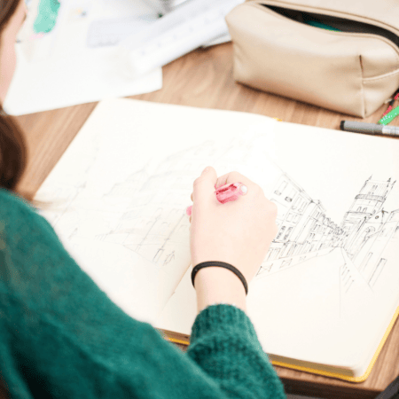 Dessin darchitecture en carnet : main dessinant une perspective urbaine au crayon.