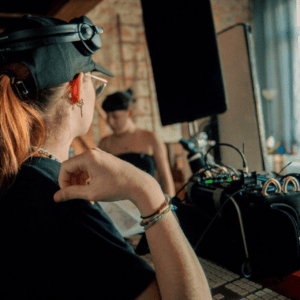 DJ en coulisses dans un loft, équipement audio, console, enceintes, casque, répétition.