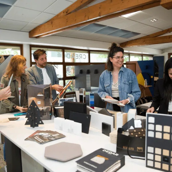 Équipe de designers sélectionnant échantillons de matériaux et de couleurs dans un studio lumineux.