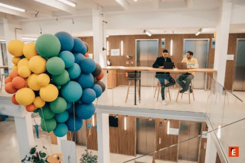 Espace coworking moderne mezzanine avec installation de ballons colorés, comptoir, ascenseurs.