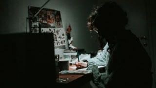 Personne dessinant au bureau la nuit, lampe focalisée, ambiance créative et intime.