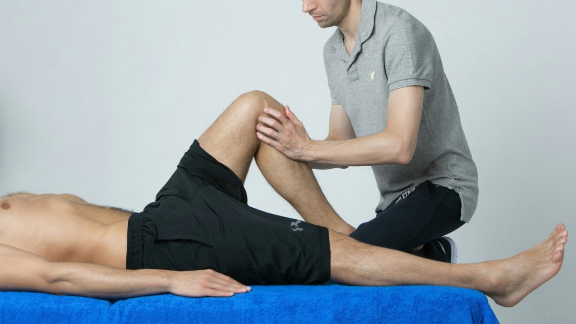 Étirement du genou en physiothérapie, thérapeute guidant la rééducation du patient.