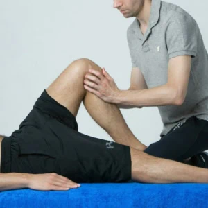 Étirement du genou en physiothérapie, thérapeute guidant la rééducation du patient.