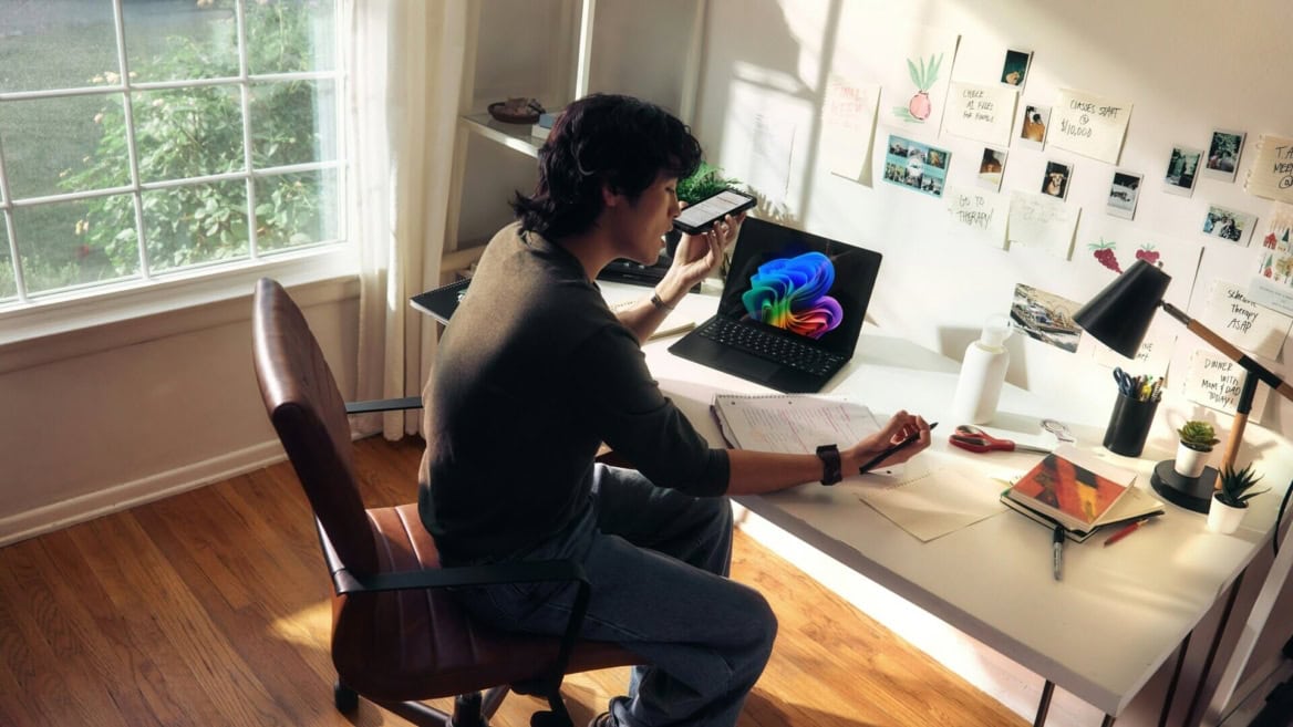 Étudiant au bureau lumineux travaillant avec téléphone, ordinateur portable, notes et plante verte.