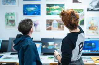 Étudiants regardant un mur dillustrations et peintures dans un atelier créatif.