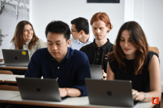 Étudiants en classe travaillant sur ordinateurs portables MacBook lors dun atelier collaboratif.