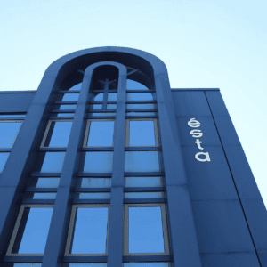 Façade architecturale moderne en verre bleu et métal, arche et lettrage blanc vertical.