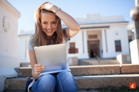 Jeune femme étudiante souriante avec tablette sur escaliers duniversité en extérieur ensoleillé.