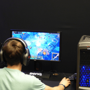 Joueur de dos devant écran BenQ, PC gaming, casque, souris et clavier.