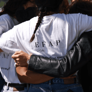 Accolade de groupe à Lyon, t‑shirts blancs et mains solidaires en gros plan.