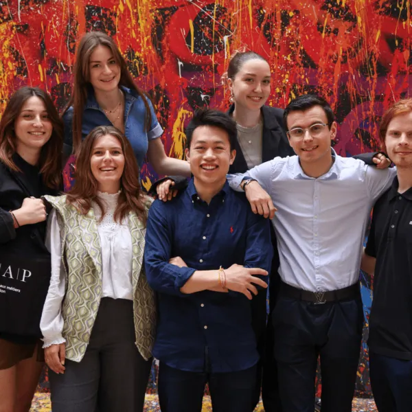 Portrait de jeunes posant devant un mural rouge vibrant de street art.