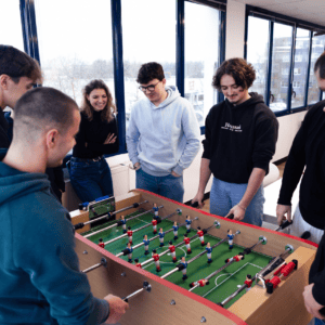 Groupe de collègues jouant au baby-foot au bureau, ambiance conviviale et pause déquipe.