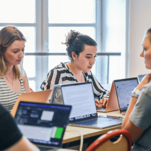 Groupe détudiants en collaboration autour dordinateurs portables pour projet de travail.