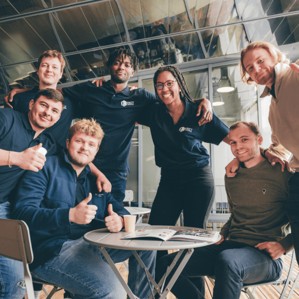 Groupe de jeunes souriants en équipe conviviale autour dune table ronde dans un café.