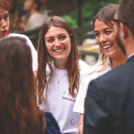 Groupe souriant en extérieur, femmes et un homme en conversation conviviale.
