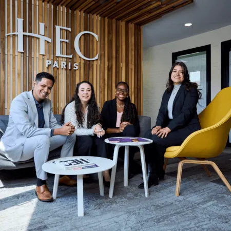 Équipe HEC Paris dans salon moderne en bois, fauteuil jaune et réception lumineuse.