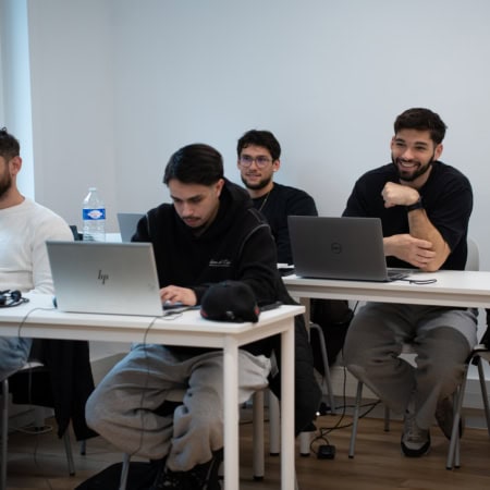 Jeunes étudiants en salle détude travaillant sur ordinateurs à la lumière naturelle.