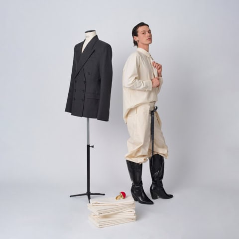 Mannequin et modèle en studio, blazer tailleur charbon, tenue crème et bottes noires.