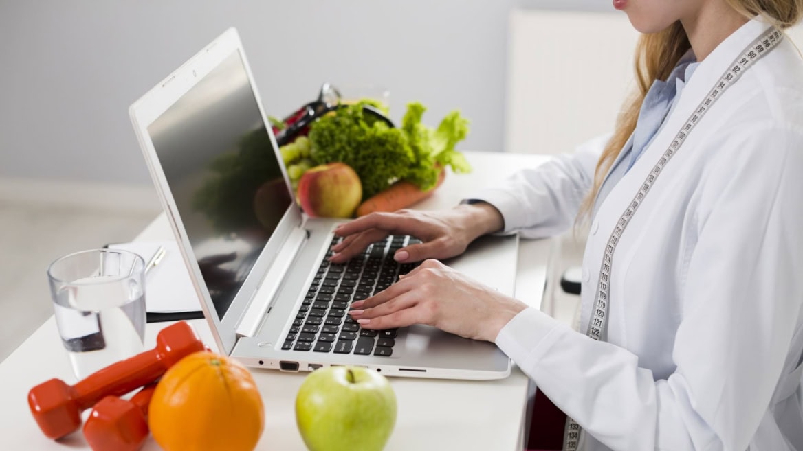 Nutritionniste en téléconsultation sur ordinateur, fruits, conseils diététiques et bien-être.