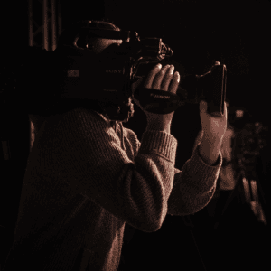 Opérateur caméra Sony Fujinon professionnel en studio, gros plan mains, éclairage dramatique.