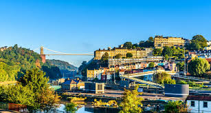 Pont suspendu sur gorge et rivière, panorama de ville et maisons en terrasses.
