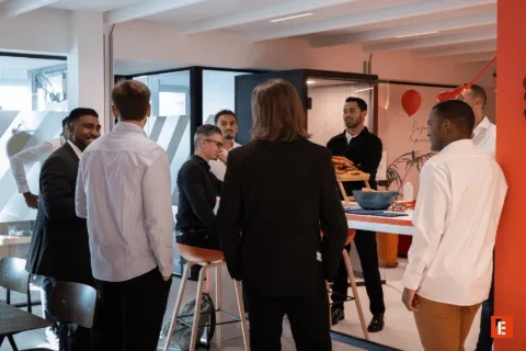 Pause café en open space : collègues discutant autour de viennoiseries dans un espace détente.