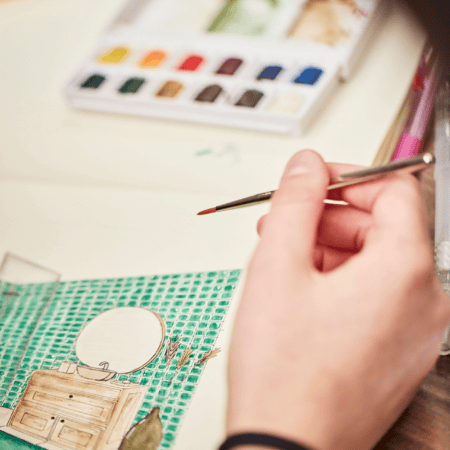 Main peignant une aquarelle dintérieur avec brosse et palette, carrelage turquoise visible.