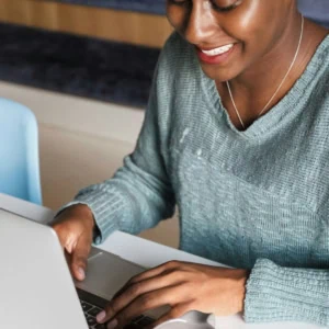 Personne travaillant sur MacBook portable à son bureau, clavier et souris.