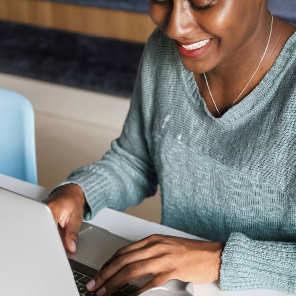Personne travaillant sur MacBook portable à son bureau, clavier et souris.