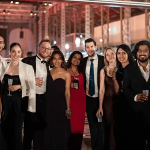 Photo de groupe en soirée élégante : invités en robes et costumes lors dun cocktail.