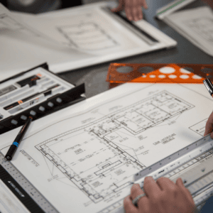 Plan darchitecte précis avec mains, règle triangulaire et stylo technique en train de mesurer.