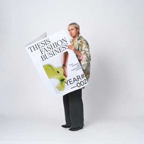 Portrait mode éditorial en studio : personne tenant grande affiche mode durable.