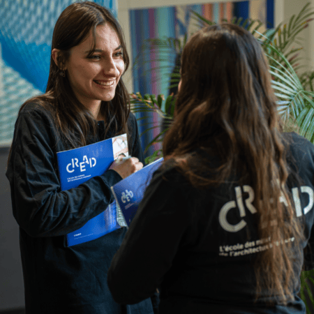 Portrait femme souriante CREAD, brochures bleues et logo visibles.