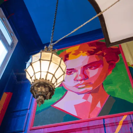 Portrait mural coloré dans hall descalier, lanterne vintage et couleurs vives.
