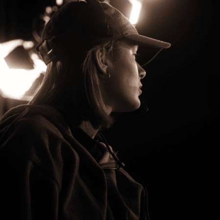 Portrait profil jeune en studio, casquette et micro, lumière darrière-plan cinématographique.