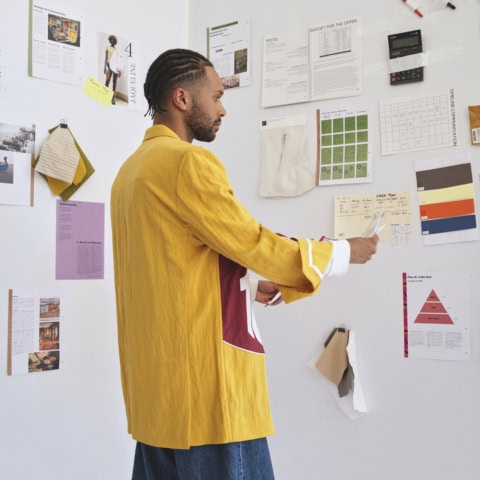 Portrait profil dun créatif devant moodboard de planche de création avec échantillons, palette et notes.