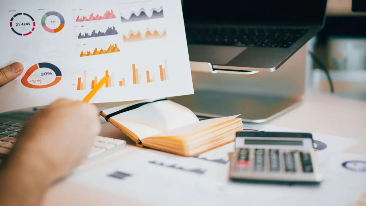 Analyse de données au bureau : graphiques, rapports, ordinateur portable et calculatrice.