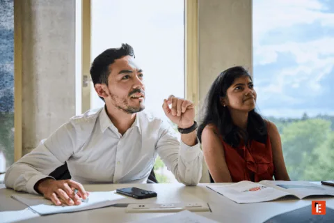 Réunion de bureau à lumière naturelle, deux collaborateurs discutant autour de documents et dun magazine.