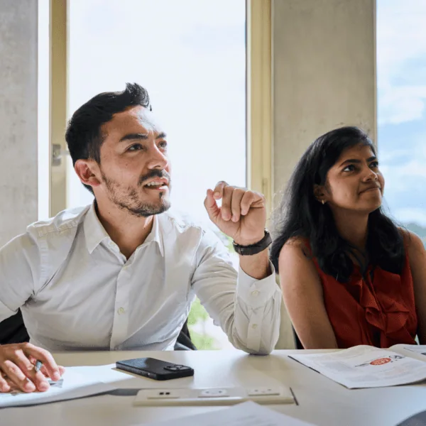 Réunion de bureau à lumière naturelle, deux collaborateurs discutant autour de documents et dun magazine.
