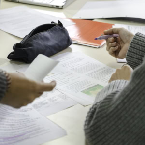 Réunion de travail collaborative, mains annotant documents près dun ordinateur portable.