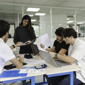 Groupe détudiants en réunion de travail collaboratif autour dune table avec ordinateurs.
