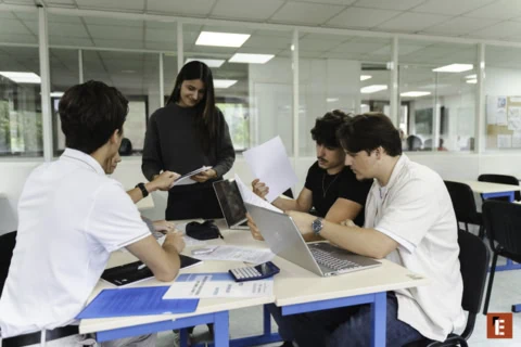 Groupe détudiants en réunion de travail collaboratif autour dune table avec ordinateurs.