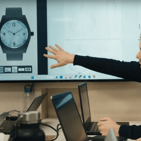 Réunion design montre : rendu 3D sur écran, designer pointant le cadran.