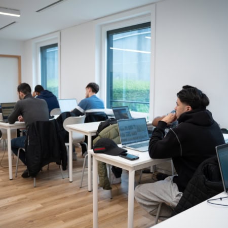 Salle de cours minimaliste moderne, étudiants avec ordinateurs portables et enseignant présentant.