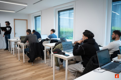 Salle de cours minimaliste moderne, étudiants avec ordinateurs portables et enseignant présentant.