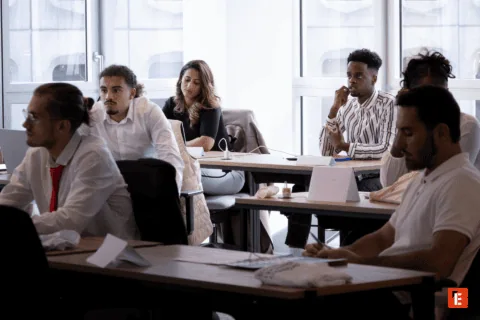 Salle de formation moderne pour atelier et réunion, participants, tables, chaises ergonomiques, grandes fenêtres.