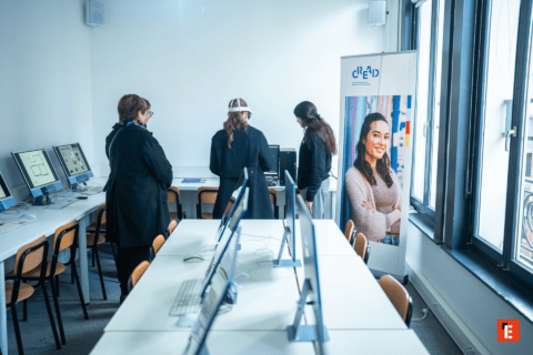 Salle informatique moderne avec rangées dordinateurs et démonstration casque réalité virtuelle.