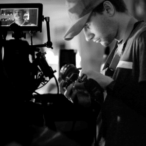 Technicien cinéma réglant une caméra et moniteur en noir et blanc, gros plan concentration.