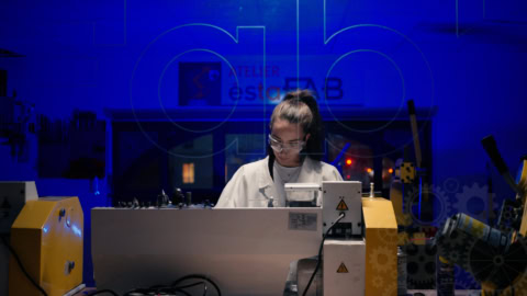 Technicien en blouse blanche travaillant sur machine industrielle dusinage dans atelier éclairé en bleu.