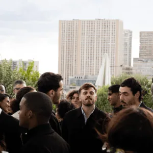 Personnes en terrasse sur toit urbain, réception conviviale avec horizon et végétation.